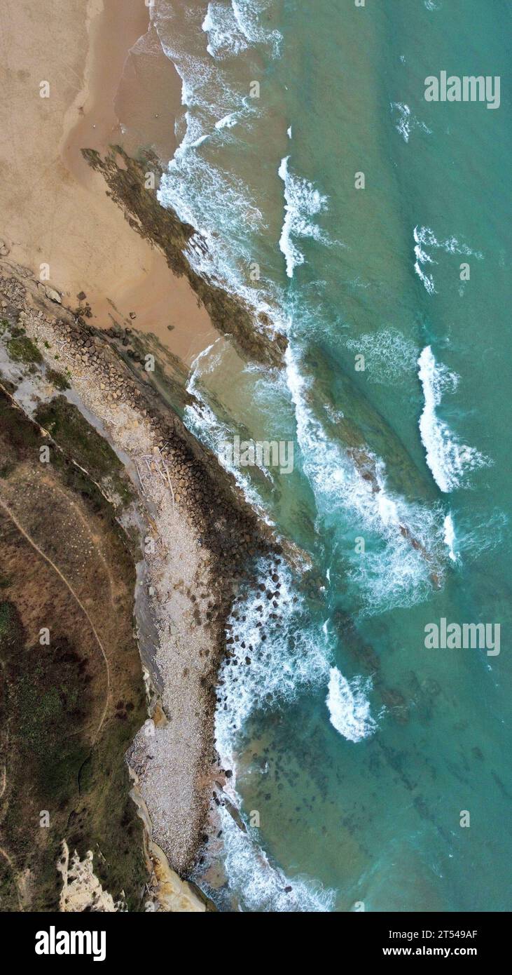Ein Blick aus der Luft auf einen sonnigen Strand, umgeben von kristallklarem, türkisfarbenem Wasser Stockfoto