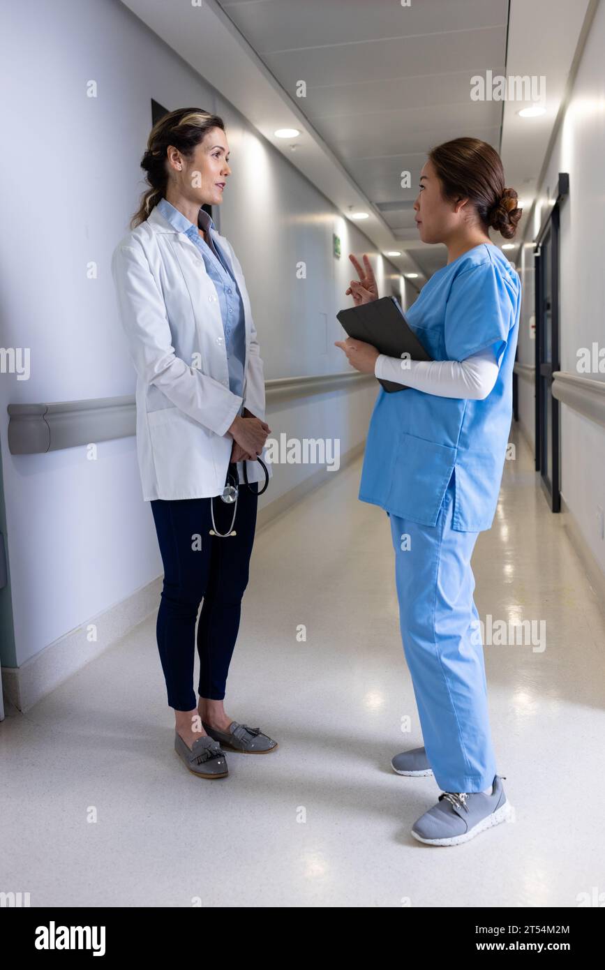 Ernsthafte Arztinnen mit Tablettendiskussion im Krankenhauskorridor Stockfoto