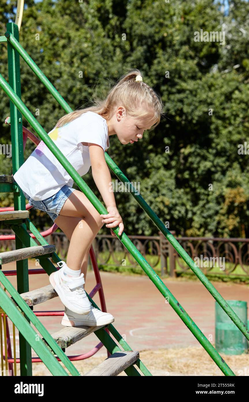 Kleines Mädchen auf einem Spielplatz im Sommer-Stadtpark. Kindheit, Freizeit und Menschenkonzept - glückliche Kinderruhe und viel Spaß Stockfoto