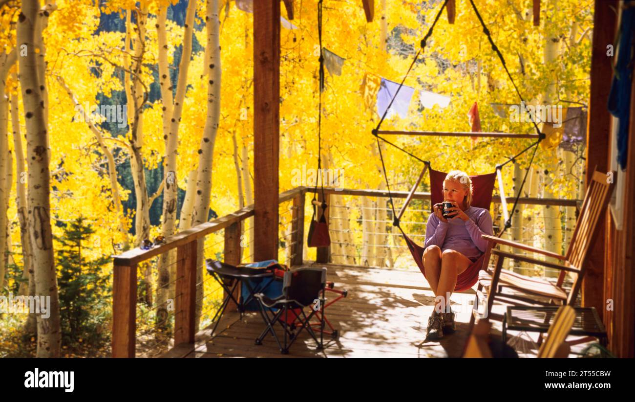 Frau, die sich in einer Berghütte im Herbstlaub entspannt. Stockfoto