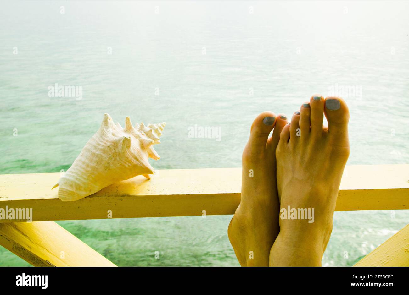 Nahaufnahme einer Muschelmuschel und der Füße einer Frau auf einem Geländer, Panama. Stockfoto