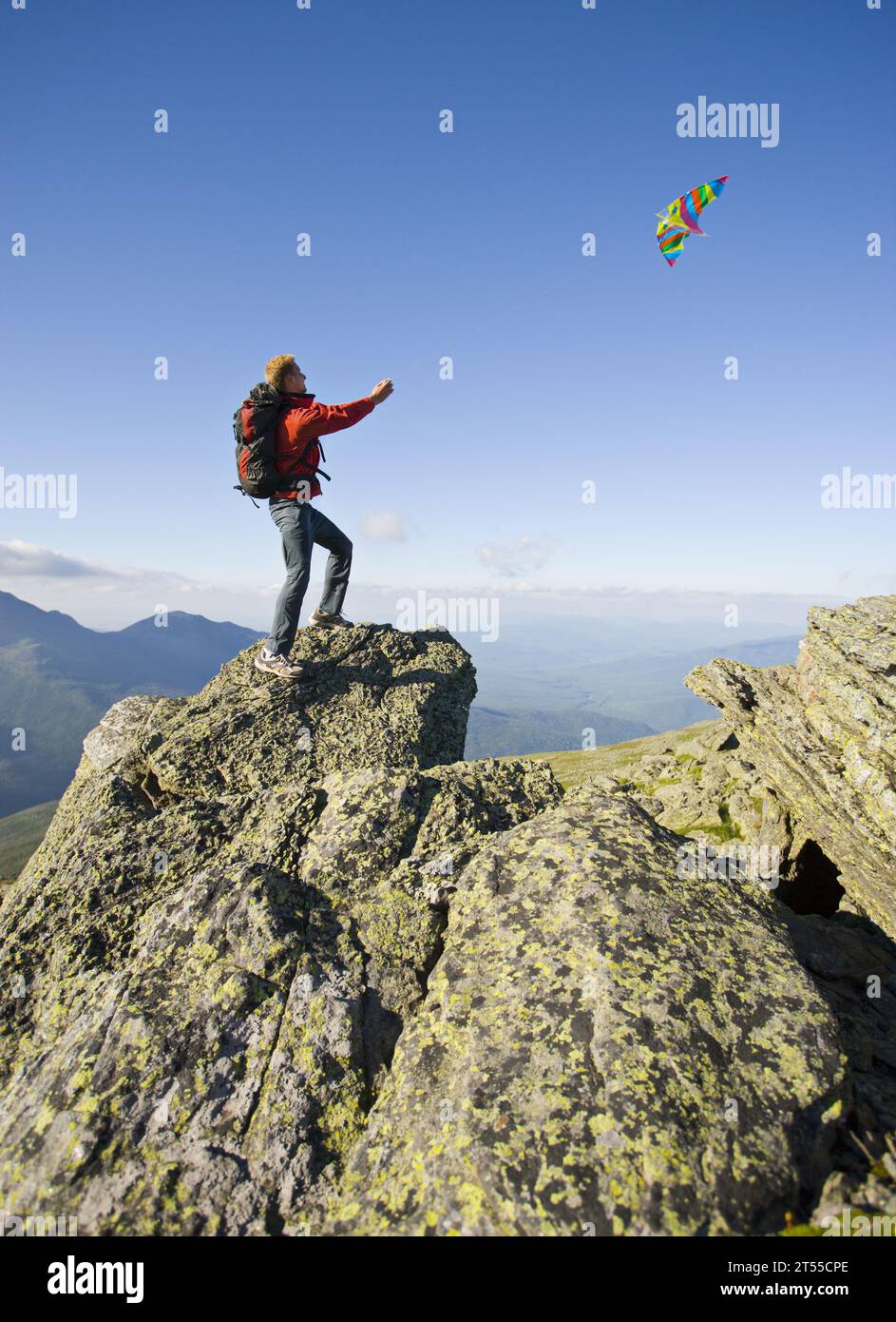 Foto eines Wanderers, der bei starkem Wind auf dem Mount Washington einen Drachen fliegt. Stockfoto