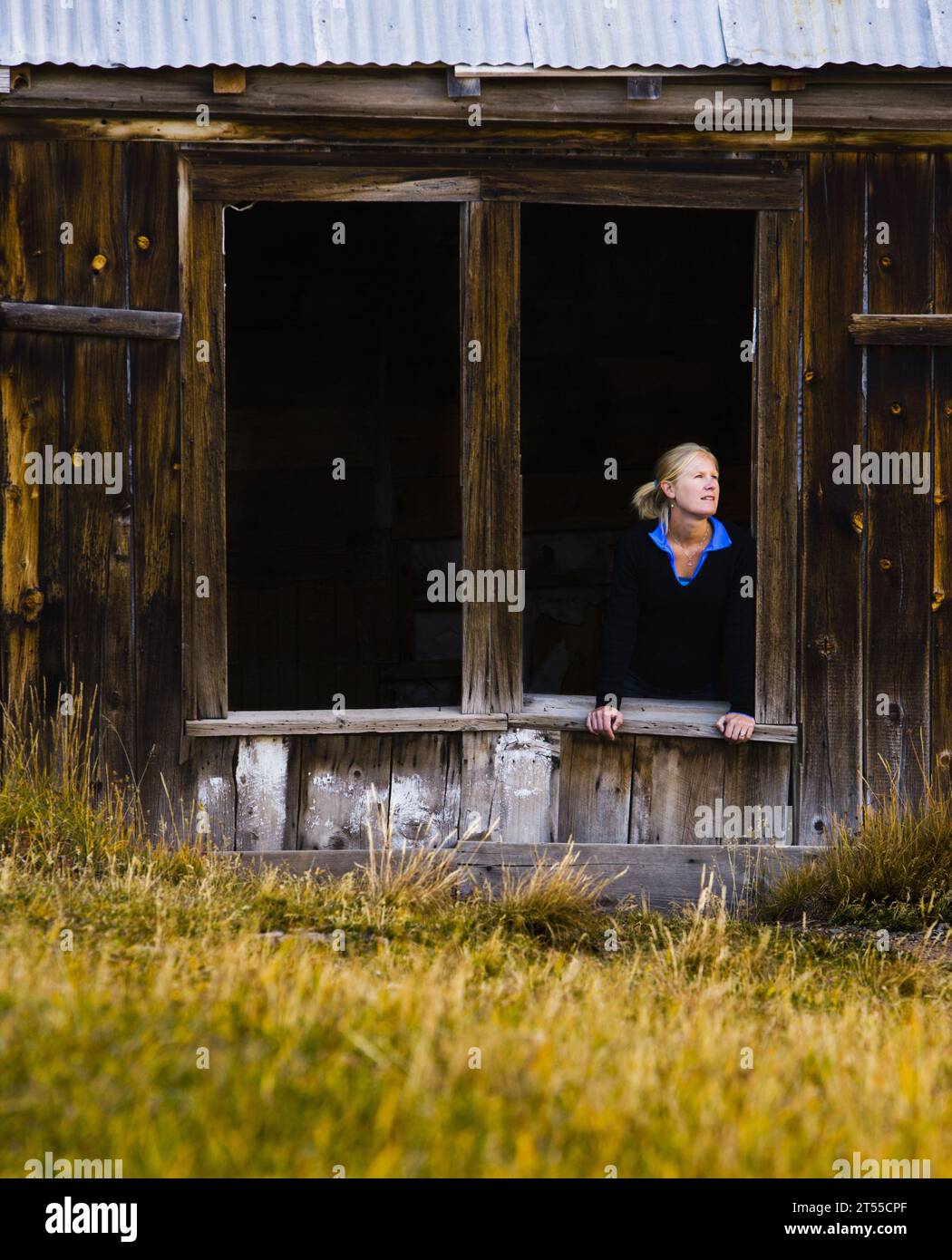Porträt einer 30-jährigen Frau, die aus einem offenen Windown in einer Geisterstadt, Colorado, blickt. Stockfoto