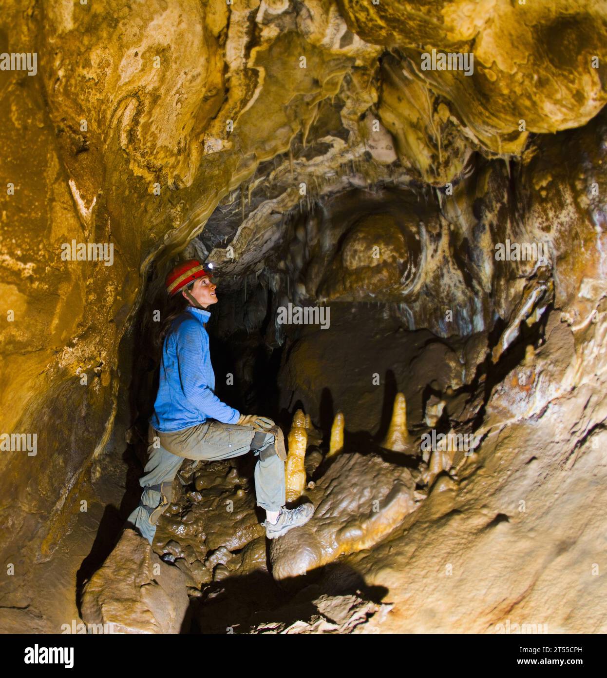 Frau mit Stirnlampe, die Stalaktiten und Stalagmiten ansieht, während sie in Höhlen Höhlen Höhlen, Colorado. Stockfoto