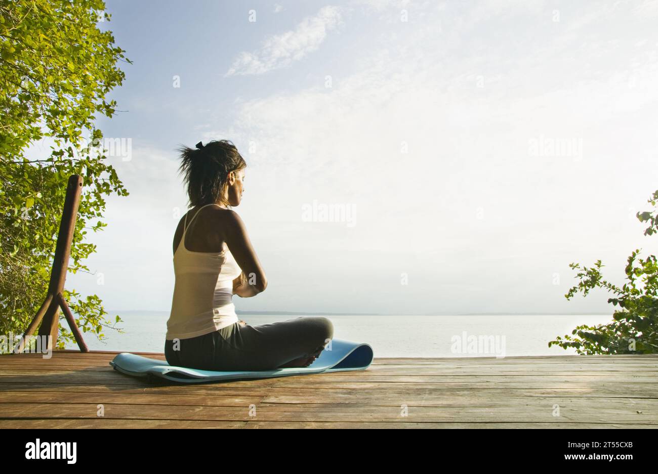 Frau übt Yoga auf einer Terrasse mit Blick auf das Karibische Meer. Stockfoto