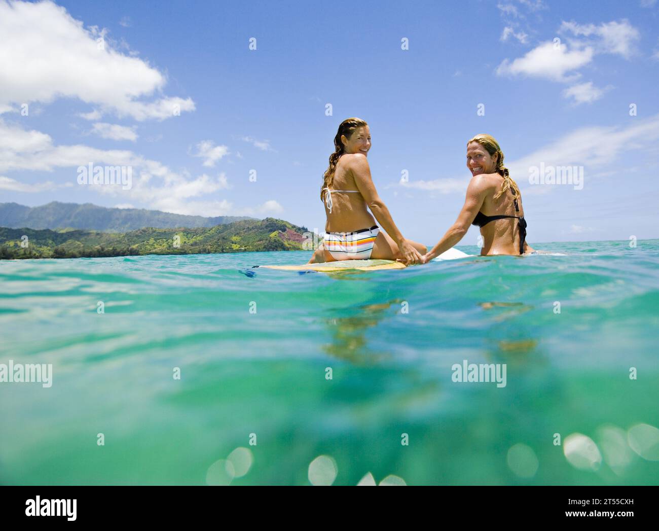 Zwei Surferinnen im Pazifik lächeln in die Kamera. Stockfoto