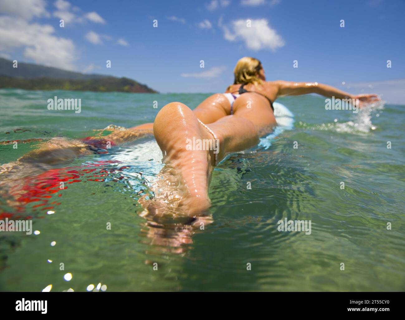 Weibliche Surferin paddelt zu den Wellen im Pazifischen Ozean. Stockfoto