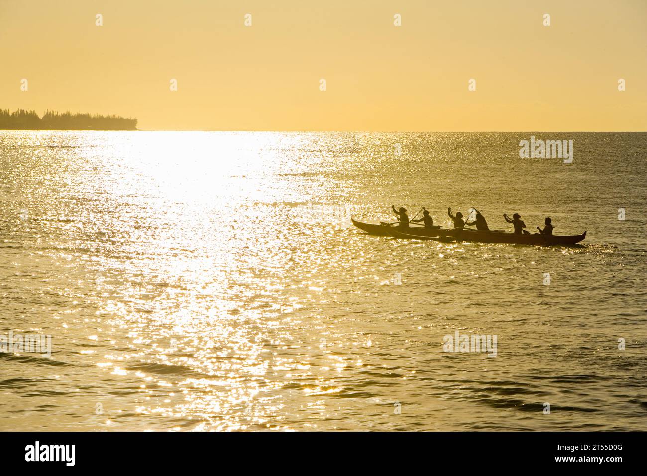 Polynesische Männer und Frauen rudern bei Sonnenuntergang auf dem Pazifik mit einem Kanu. Stockfoto