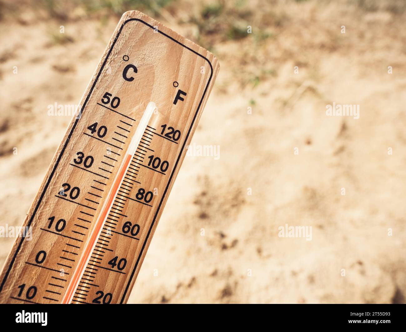 Holzthermometer mit hohen Temperaturen über 36 Grad Celsius an sonnigem Tag auf trockenem Sandboden. Begriff der Hitzewelle, des Warmweetes Stockfoto