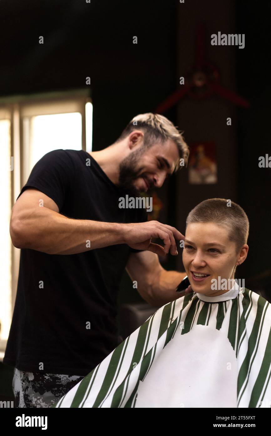 Eine Stylistin schneidet eine Frau mit einem Haarschneider kurz. Stockfoto