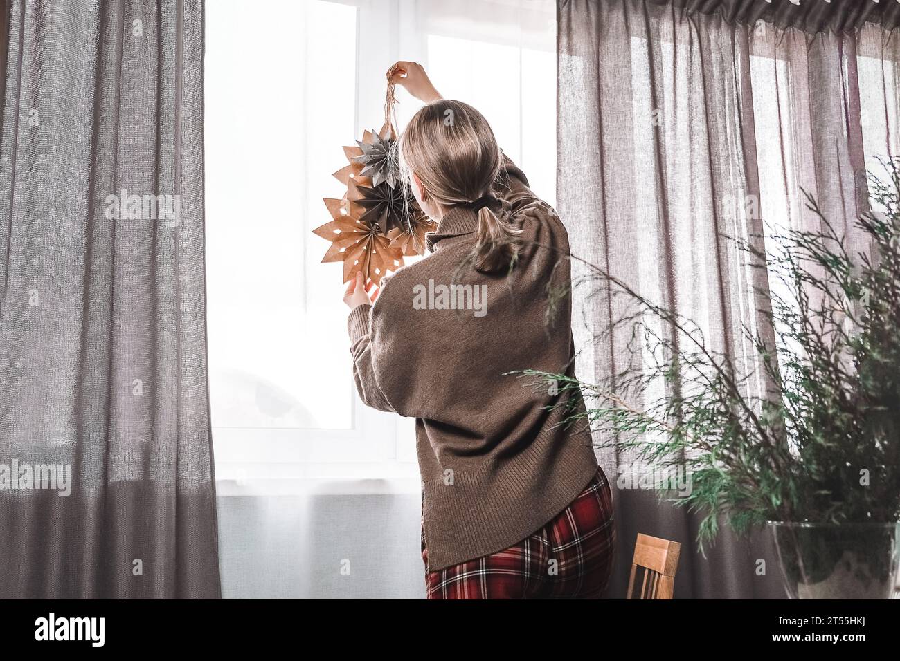 Frau, die Haus und Fenster zu weihnachten mit Papiersteinen dekoriert Stockfoto
