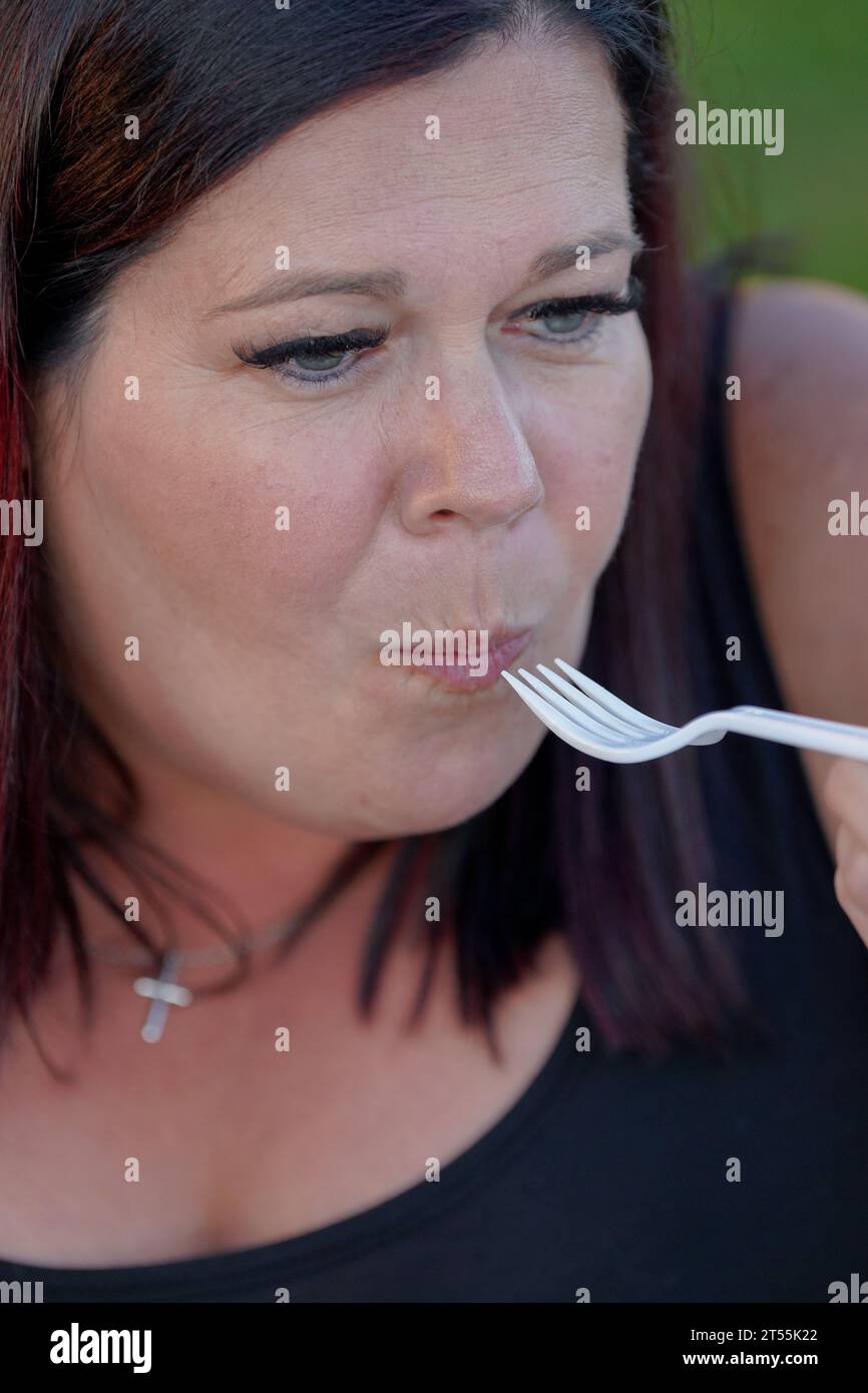 Nahaufnahme einer Dame, die einen Biss Essen isst Stockfoto