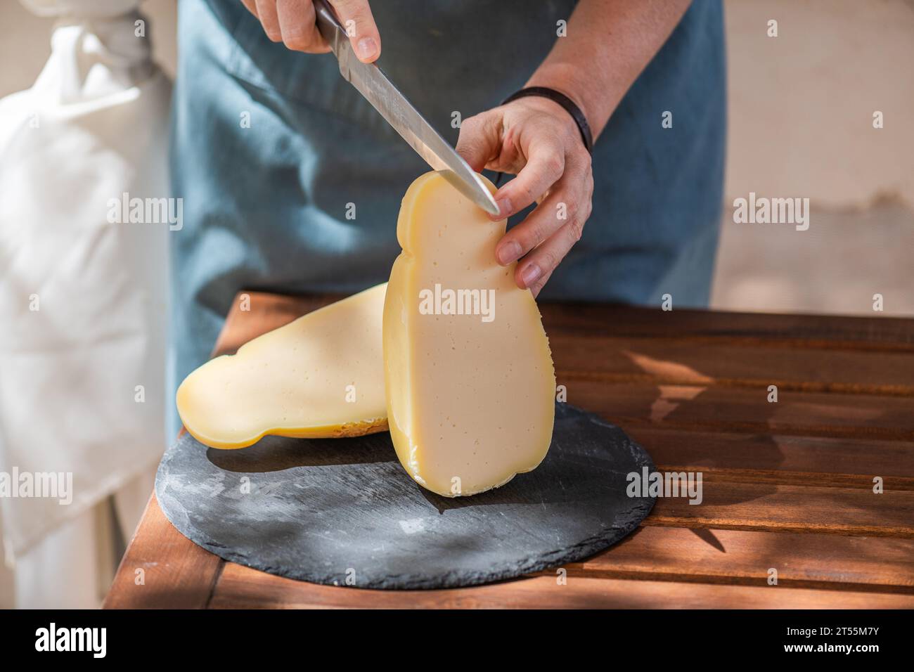 Weibliche Hand schneidet einen Caciocavallo silano Käse auf einem Schneidebrett Stockfoto