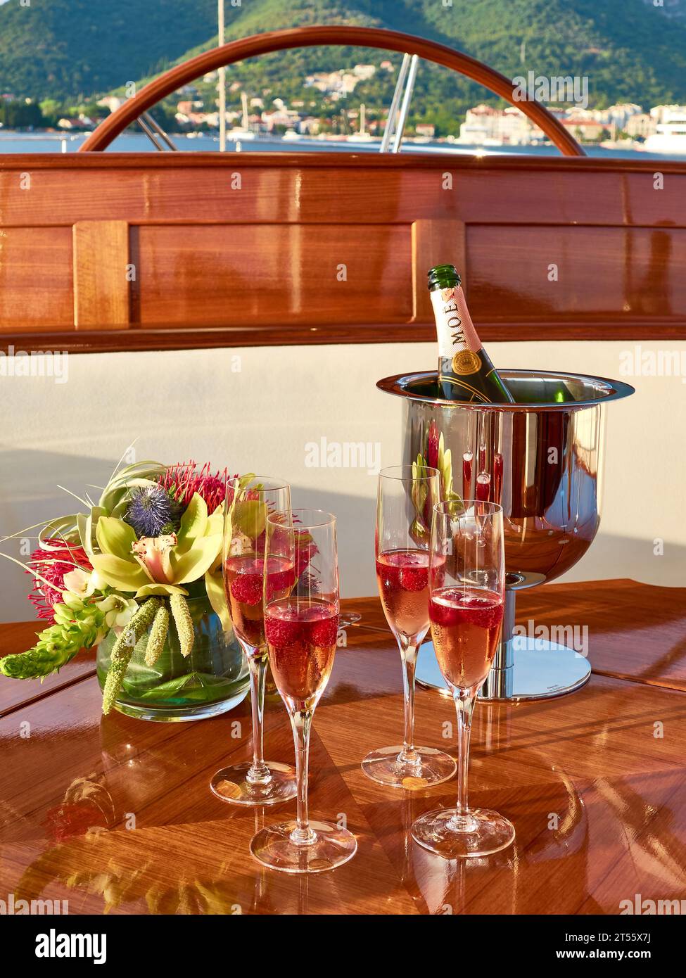 Gläser Moet Pink Champagner mit einem Eiskübel auf einem wunderschönen lackierten Teaktisch im Cockpit einer luxuriösen Segelyacht. Stockfoto