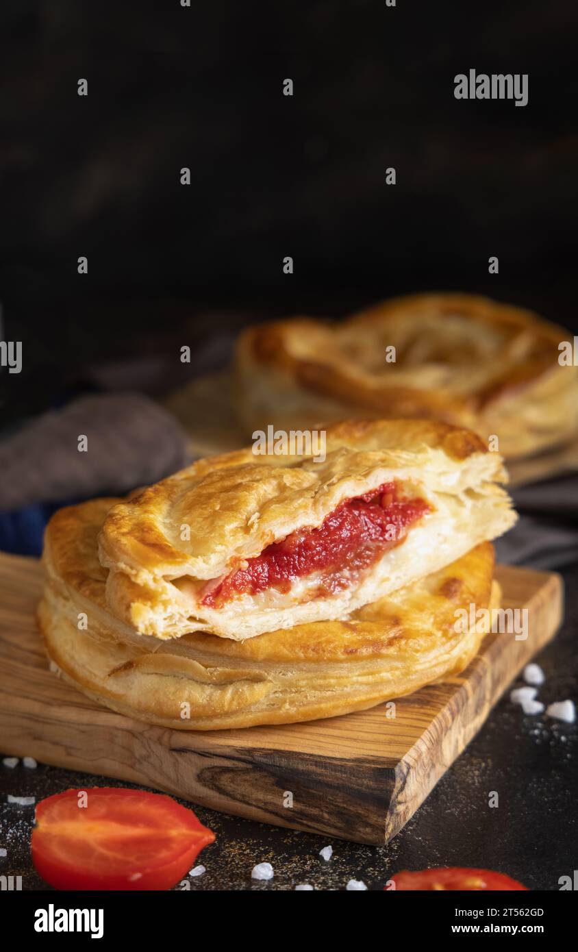 Rustico traditioneller Blätterteig gefüllt mit Bechamelsauce, Tomaten und Mozzarella, Nahaufnahme auf einem dunklen Tisch, Kopierraum. Traditionelle Straße f Stockfoto