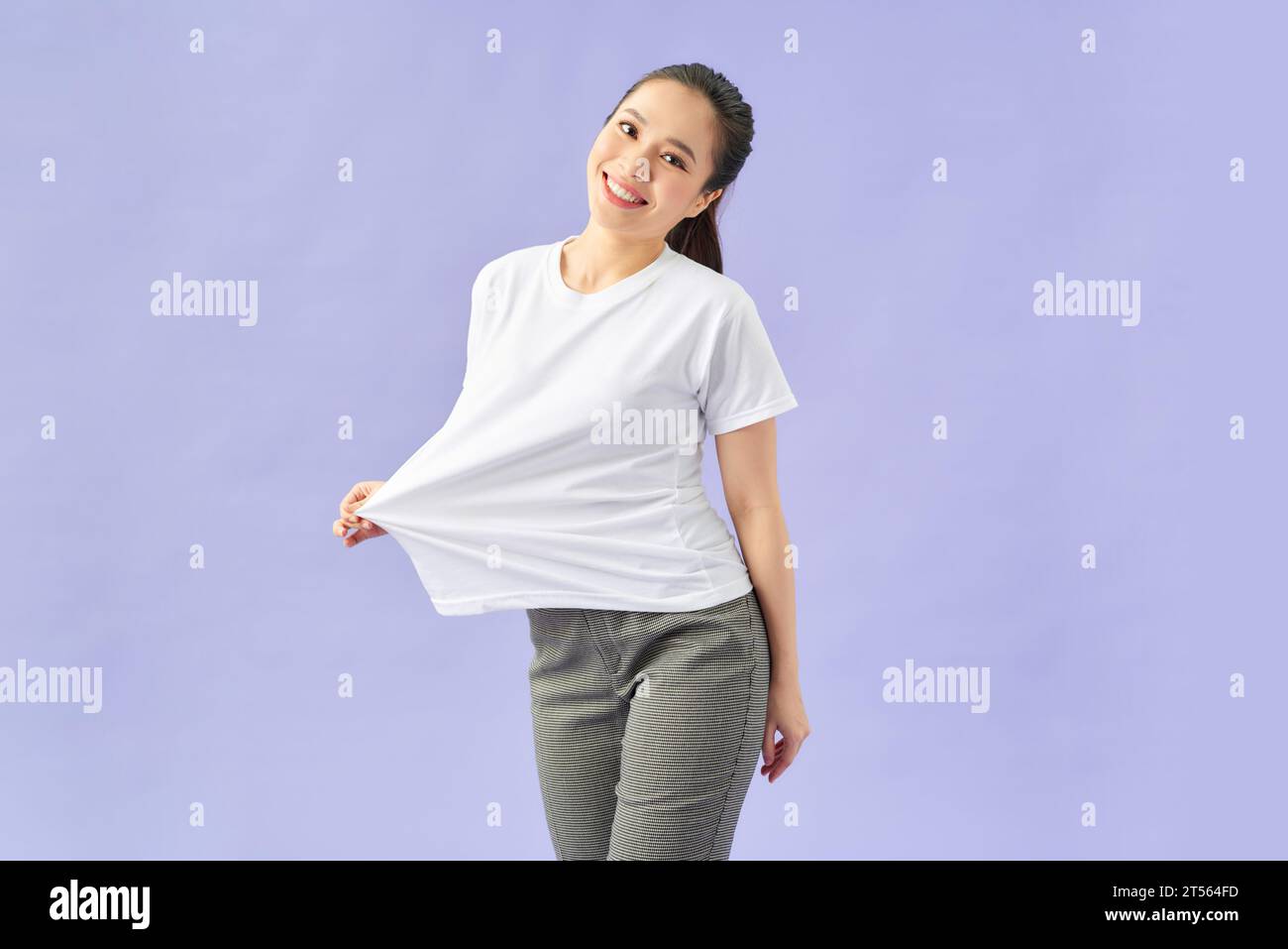 Schlanke Frau mit großem T-Shirt, isoliert auf Violett Stockfoto