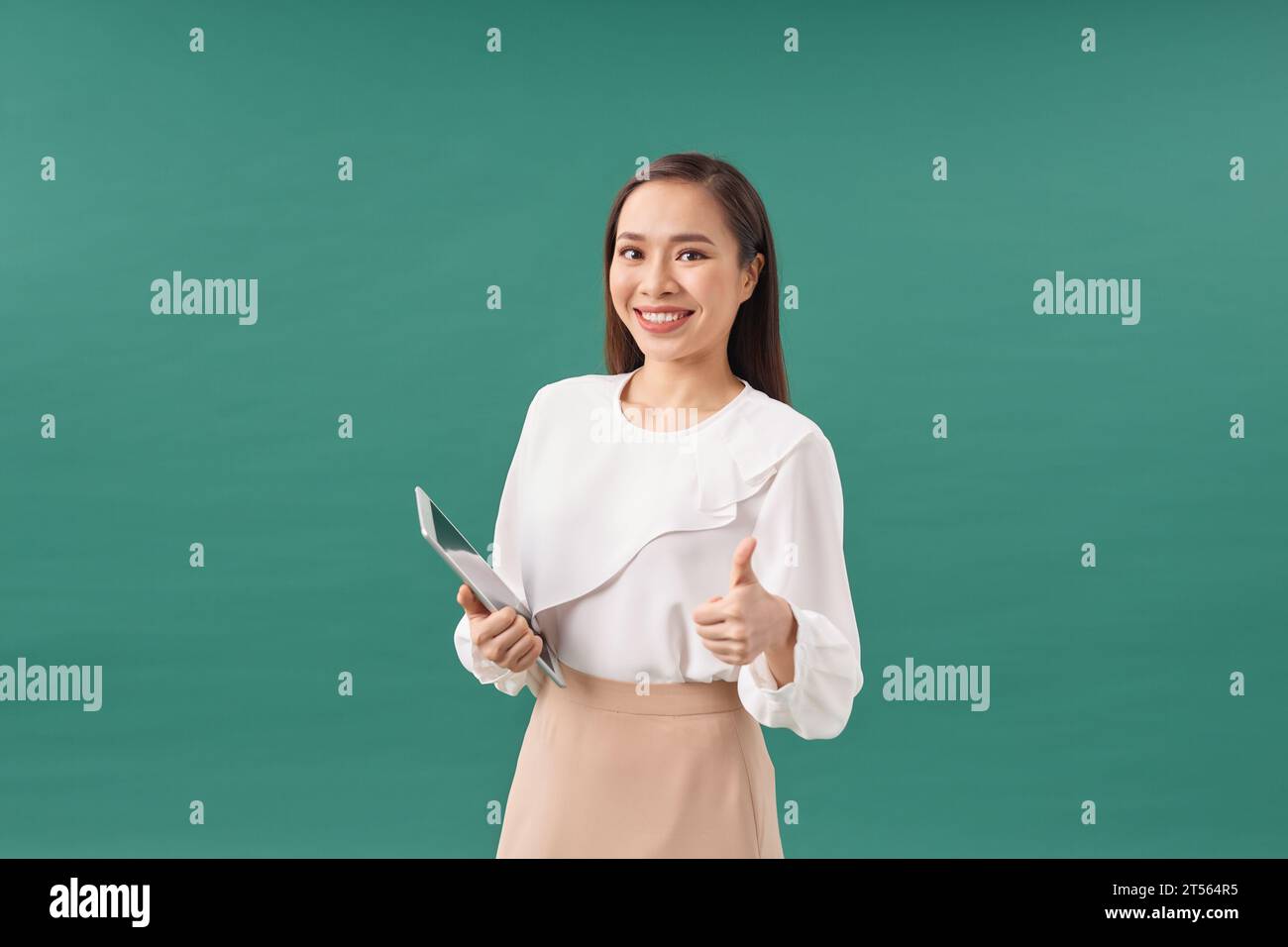 Attraktive Geschäftsfrau in formeller Kleidung hält ein Tablet und lächelt in Richtung Kamera Stockfoto