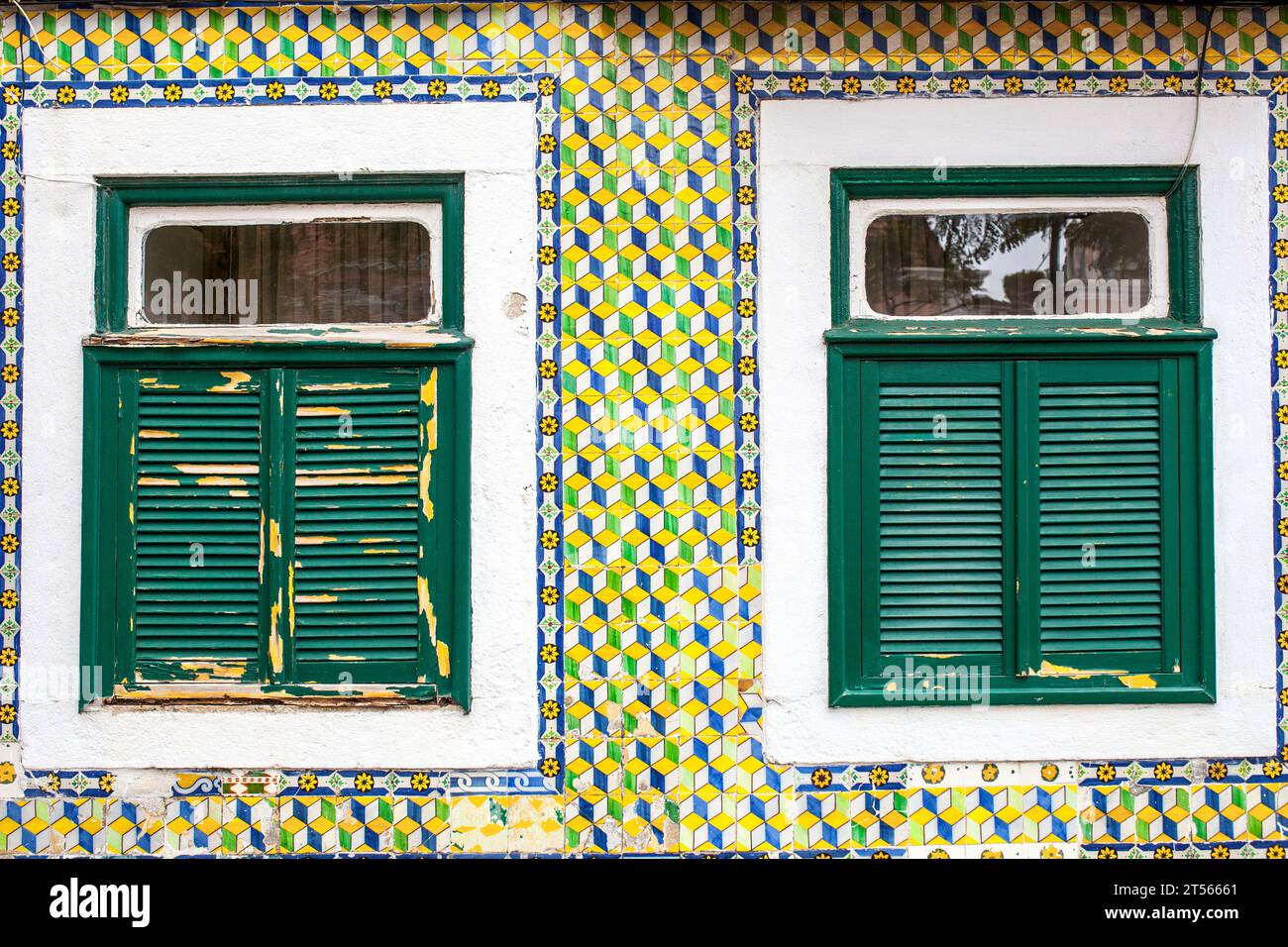 Zwei verwitterte Fenster über der gefliesten verglasten Fassade. Belem Viertel, Lisboa, Portugal Stockfoto