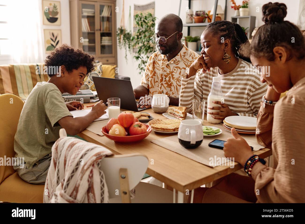 Fröhliche schwarze Familie, die am großen Tisch frühstückt Stockfoto