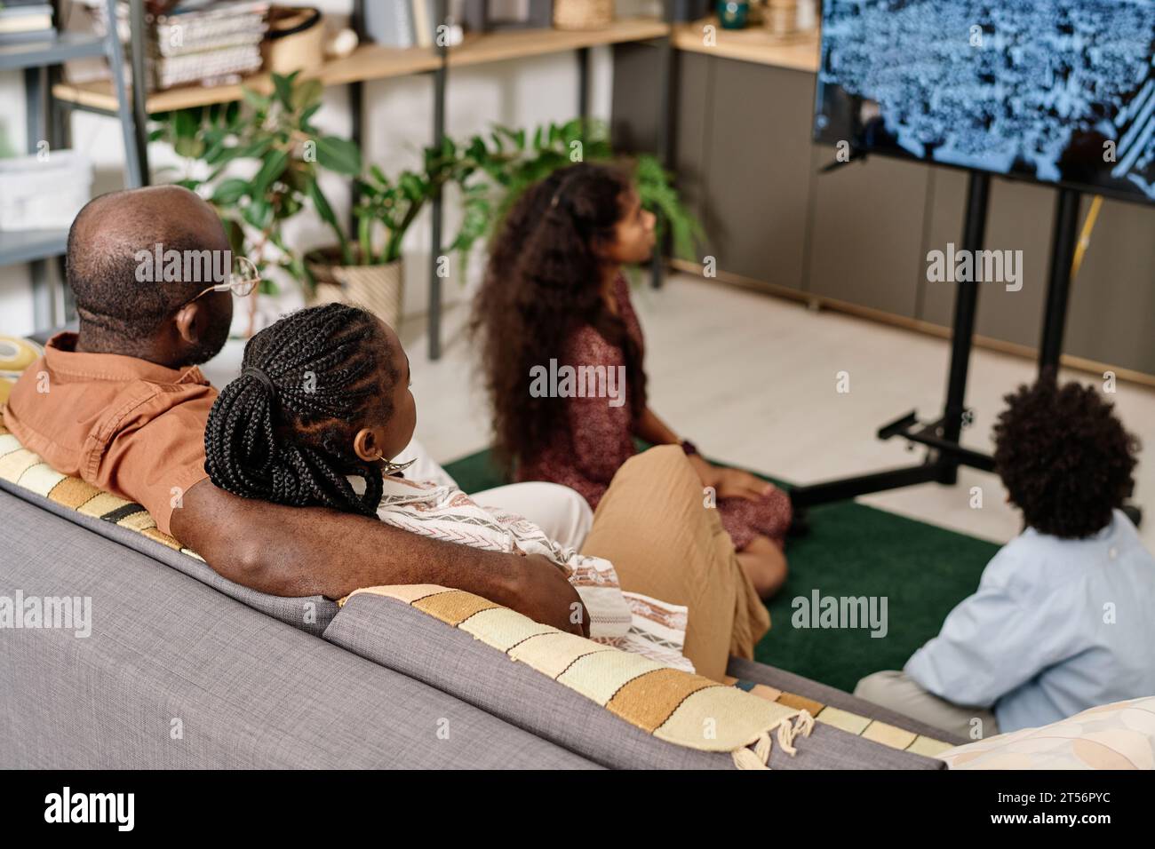 Schwarze Familie, die Martin Luther King Jr vor der Menge im fernsehen spricht Stockfoto