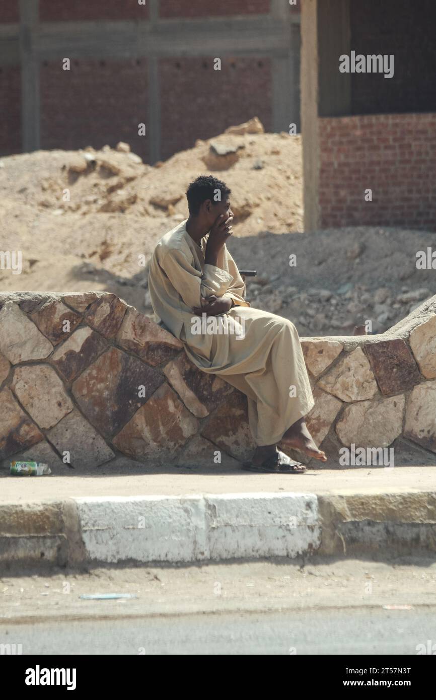 Ein arabischer Kerl sitzt vor dem Hintergrund eines zerstörten Hauses Stockfoto
