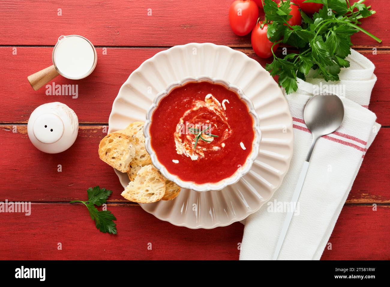 Suppe. Tomatencremesuppe oder Gazpacho mit Kräutern, Gewürzen, Kirschtomaten und Petersilie in einer weißen Schüssel auf altem rotem Holzhintergrund. Gesundes Gemüse so Stockfoto