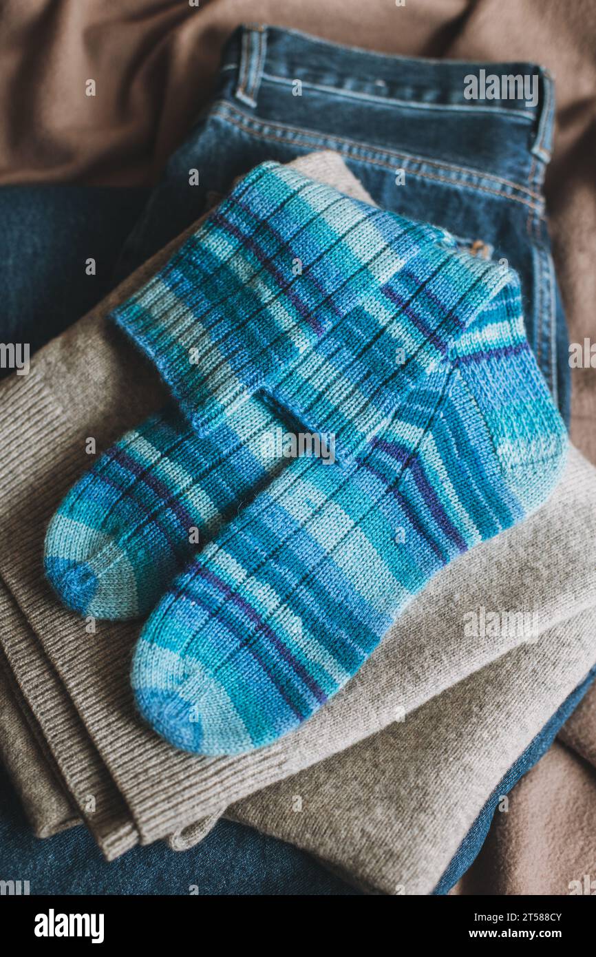 Handgestrickte blaue Socken mit Pullover und Jeans. Konzept für handgemachte und hygge Slow Life. Stockfoto