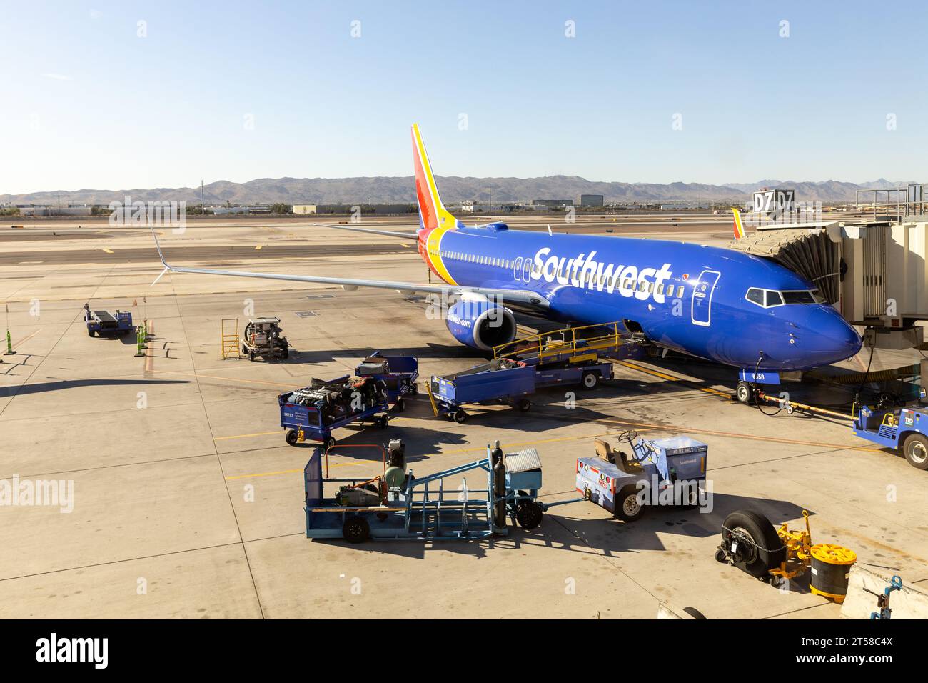 Die Piste des Phoenix Sky Harbor International Airport mit einem Flugzeug der Southwest Airlines, das an einem Gate geladen wird, und Bergen in der Ferne. Stockfoto