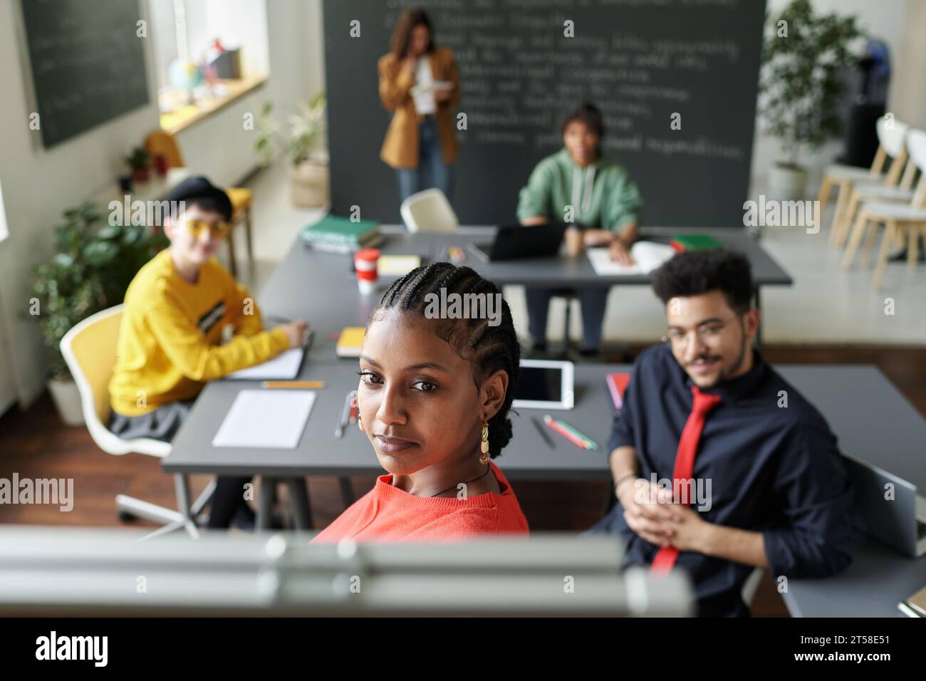 Afroamerikanerin, die beim Unterricht im Klassenzimmer Flipchart benutzt, diskutiert Themen mit anderen Schülern Stockfoto