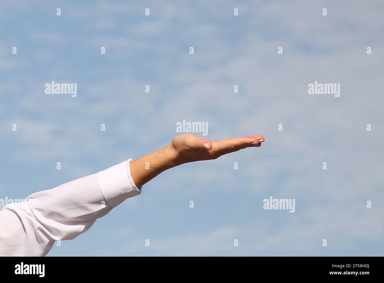 HAND EINER GLÜCKLICHEN FRAU VOLLER DANKBARKEIT, DIE MIT BLAUEM HIMMEL IM HINTERGRUND AUFTAUCHT Stockfoto