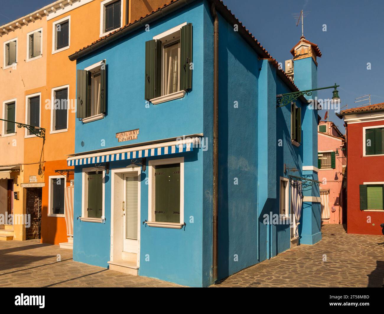 Bunte Häuser von Burano, Venedig, Italien. Blick von einer Straßenecke, Gelb, Blau, Zinnrot, Rosa. Stockfoto