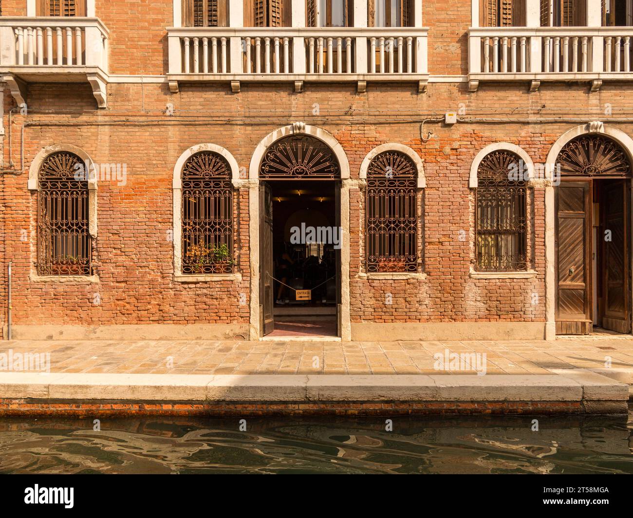Fassade einer venezianischen Villa am Rande eines Kanals. Die Fenster haben schmiedeeiserne Gitter. Wir können die Balkone oben sehen. Stockfoto