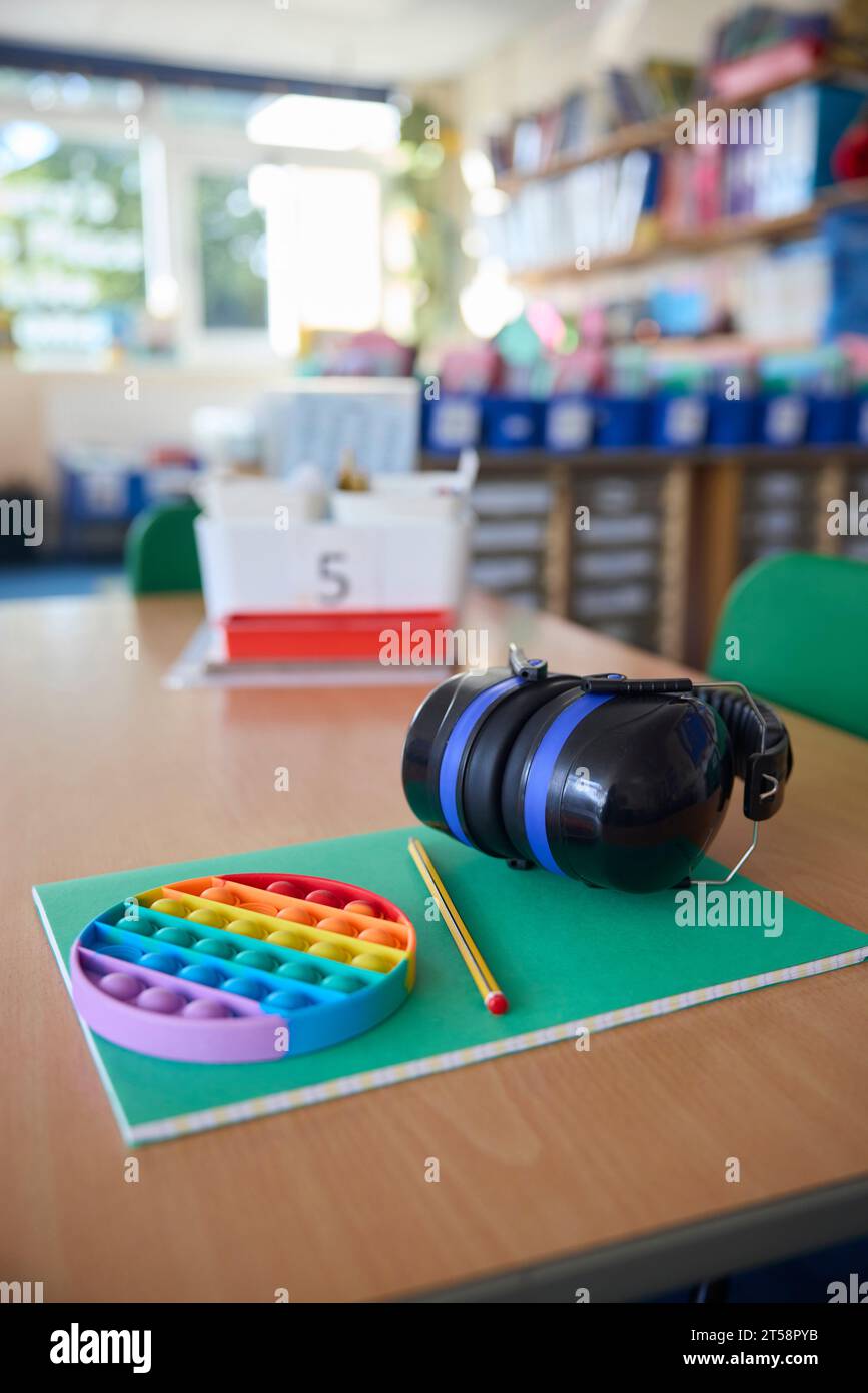 Ohrenschützer oder Kopfhörer und zappeln Spielzeug, um Kindern mit ASD oder Autismus auf dem Tisch im Schulunterricht zu helfen Stockfoto