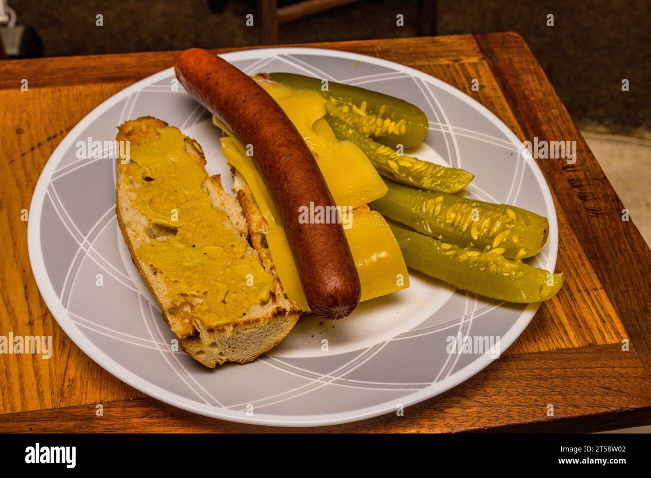 Ein Sandwich mit französischem Baguette und dijon-Senf, norwegischem Jarlsberg-Käse, polnischem Hotdog und amerikanischer Dill-Gurke auf der Seite. Stockfoto