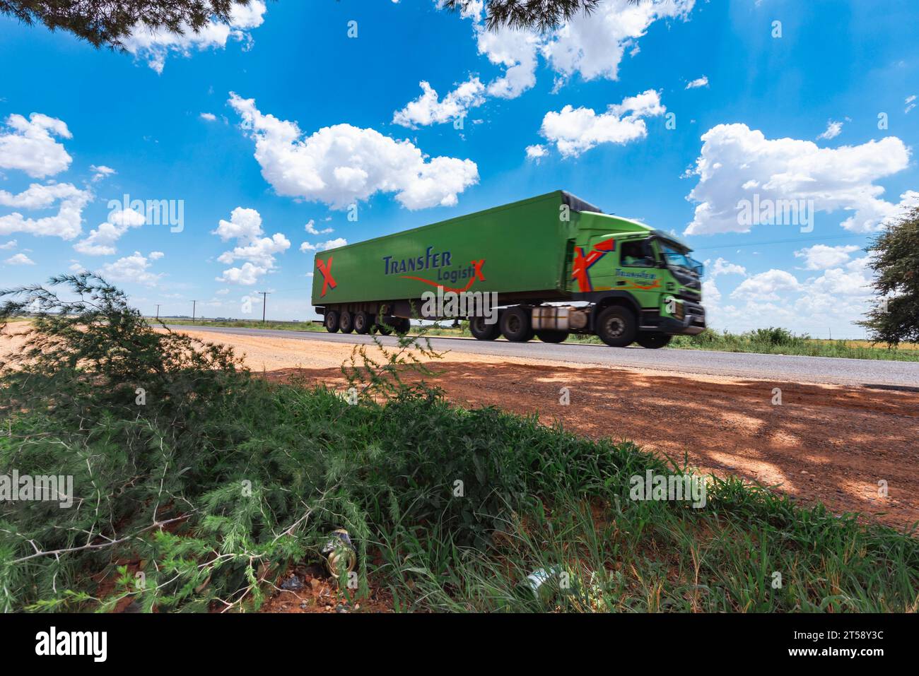Ein großer grüner Transportwagen fährt an einem schönen Tag in Südafrika entlang einer ruhigen Straße Stockfoto