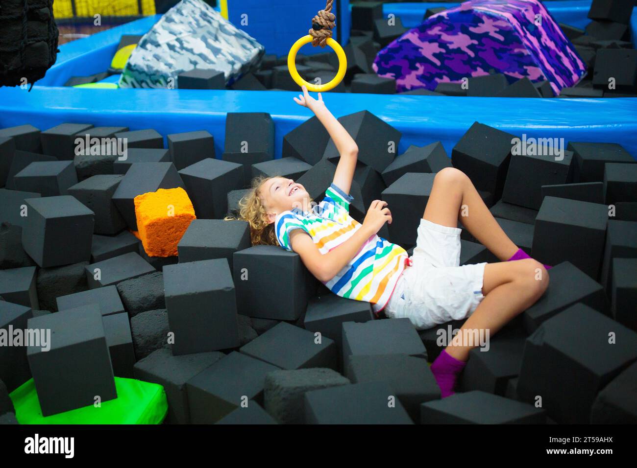 Kind springt im Trampolin-Park. Hüpfspaß auf Kindergeburtstag. Indoor-Spielplatz mit hüpfender Burg. Gesunde Aktivität für Kinder. Stockfoto