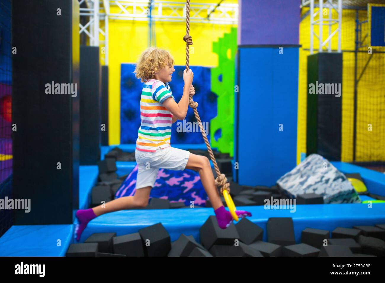 Kind springt im Trampolin-Park. Hüpfspaß auf Kindergeburtstag. Indoor-Spielplatz mit hüpfender Burg. Gesunde Aktivität für Kinder. Stockfoto
