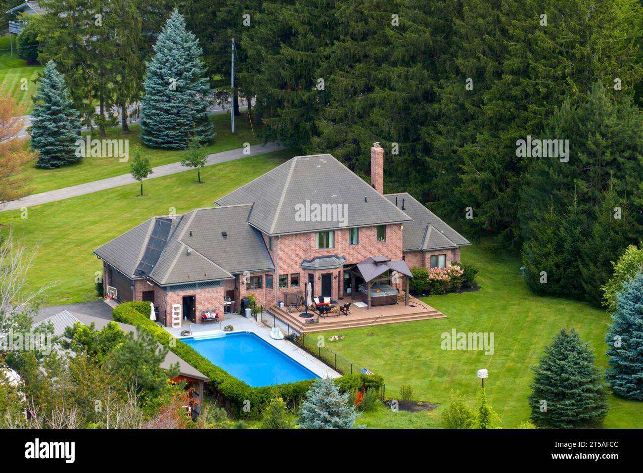 Gehobenes Vorstadthaus mit großem Swimmingpool im Hinterhof und grünem Rasen in der Sommersaison im Upstate New York. Privates Wohnhaus in Stockfoto