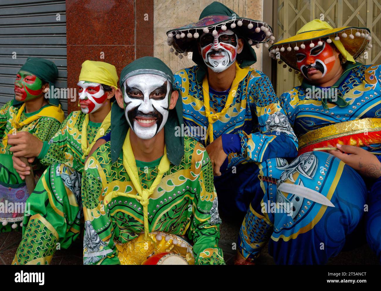 Mitglieder einer Lion Dance Truppe mit exotischem Kleid und bunt bemalten Gesichtern warten auf ihre Aufführung in einem taoistischen Schrein in Bangkok, Thailand Stockfoto