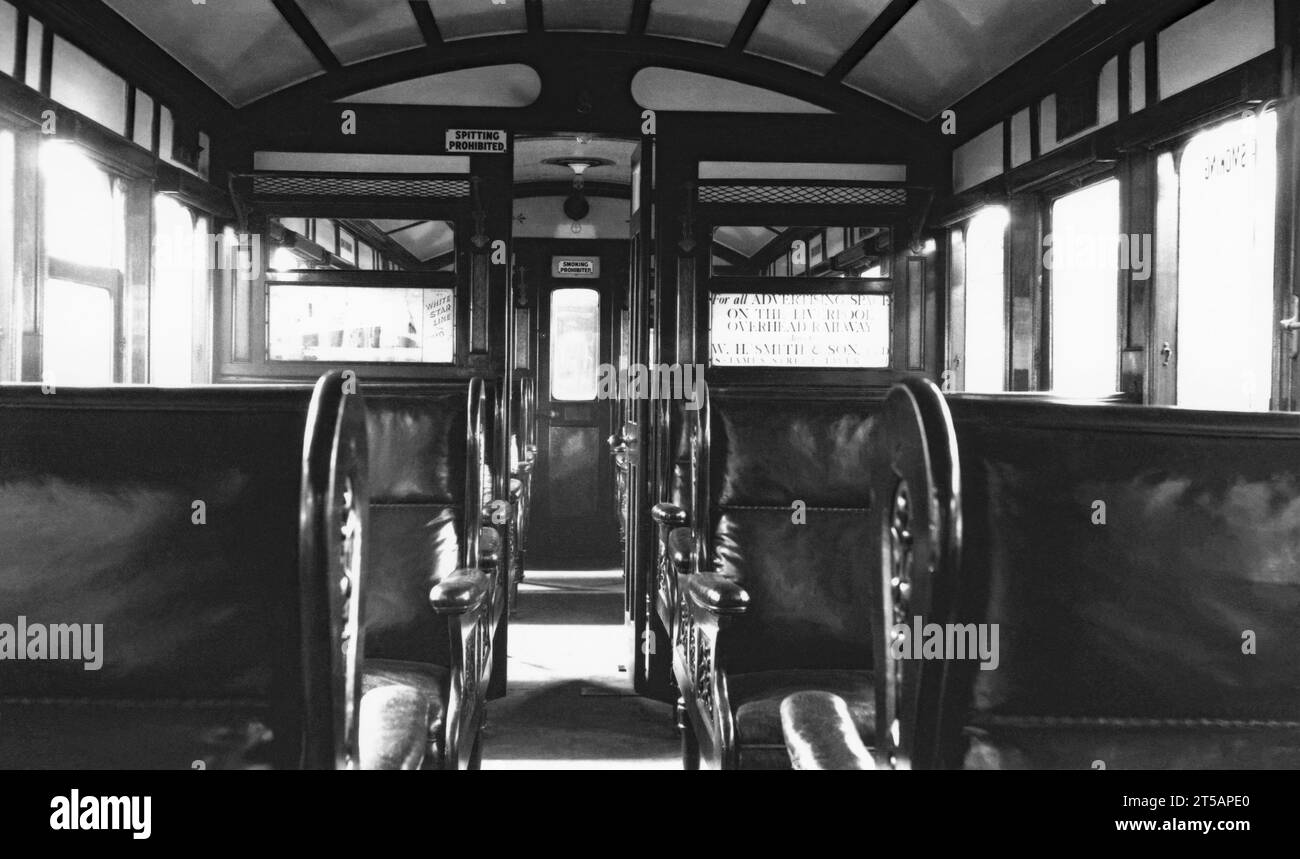 Das Innere eines ersten-Klasse-Wagens in den elektrischen Zügen mit Holzkarosserie der Liverpool Overhead Railway, Merseyside, England, UK um 1950. Die Sitze sind mit Leder verkleidet, und die Schilder im Fahrzeug weisen auf „Rauchen verboten“ und „Spucken verboten“ hin. Die Liverpool Overhead Railway verkehrte entlang der Liverpool Docks und wurde 1893 eröffnet. Sie war die weltweit erste elektrische Hochbahn und die zweitälteste elektrische U-Bahn der Welt. Auf ihrem Höhepunkt nutzten jedes Jahr fast 20 Millionen Menschen die Bahn. Ein Bericht aus dem Jahr 1955 zeigte, dass es unerschwingliche Reparaturen erforderte und die Bahn 1956 stilllegte. Stockfoto