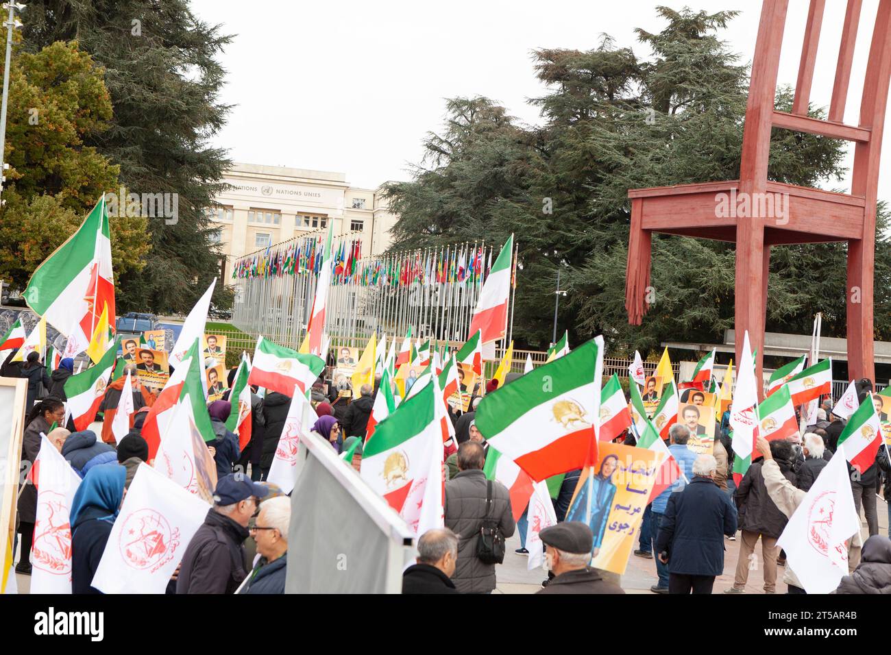 Genf, Schweiz. November 2023. Die Demonstranten tragen die ursprünglichen dreifarbigen iranischen Fahnen mit dem Aufdruck Löwe und Sonne, während andere das Emblem der wichtigsten iranischen Oppositionsgruppe, der Mudschahedin-e Khlaq (PMOI/MEK), während einer Kundgebung tragen. Hunderte Anhänger des Nationalen Widerstandsrates des Iran (NCRI) nehmen an einer Kundgebung im Palais des Nations vor dem Europäischen Hauptquartier der Vereinten Nationen Teil, um gegen die Ernennung des iranischen Regimegesandten zum Vorsitzenden des Sozialforums des UN-Menschenrechtsrates zu protestieren. Quelle: SOPA Images Limited/Alamy Live News Stockfoto