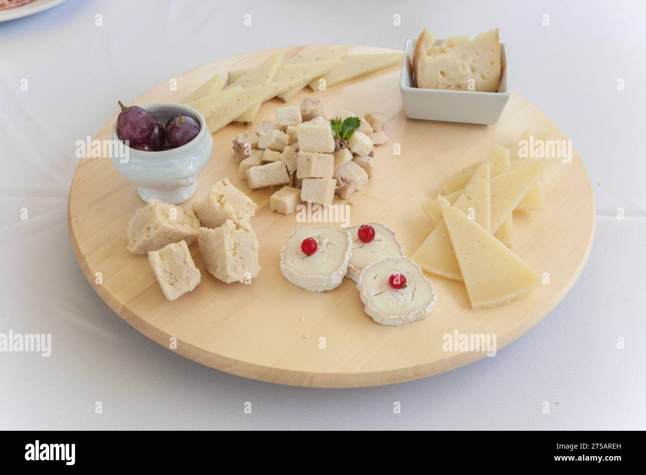 Spanisches Käsesortiment auf rotierendem Tablett. Abgerundetes Holzdisplay über dem Tisch Stockfoto