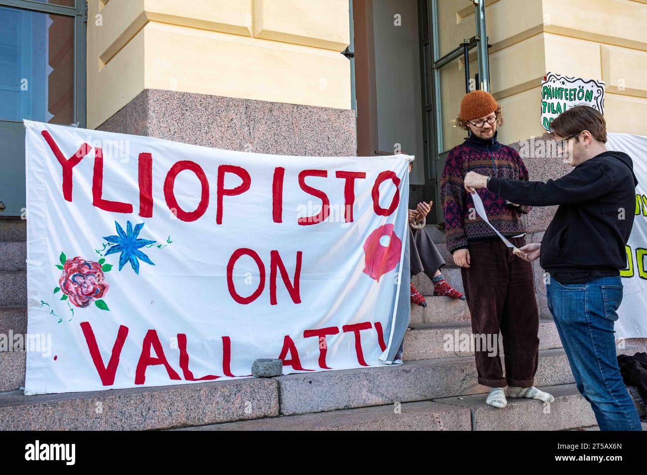 Yliopisto am Vallattu. Banner und Studenten vor der Universität Helsinki während eines Sitzungsprotests gegen Budgetkürzungen in Helsinki, Finnland. Stockfoto