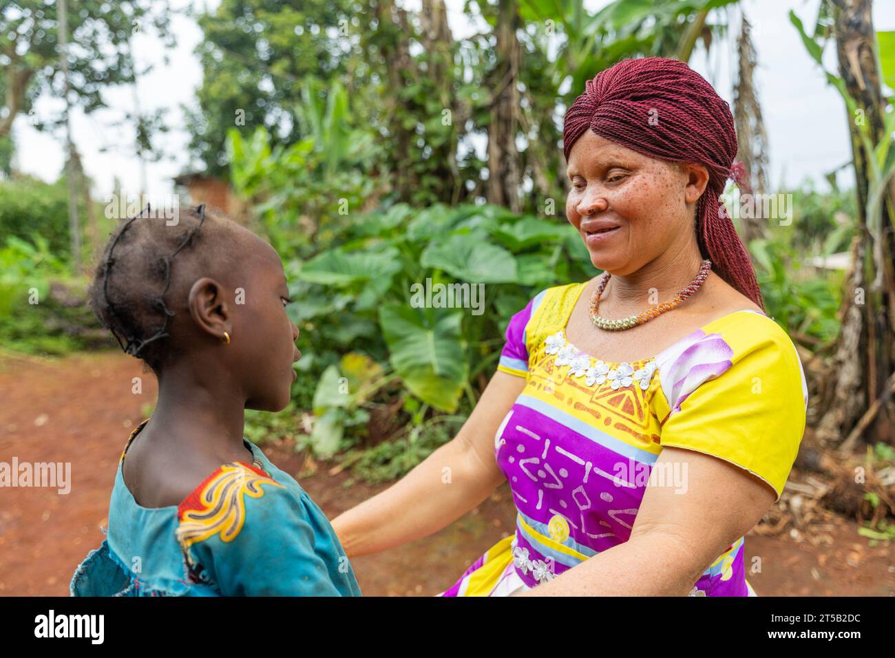 Das kleine afrikanische Mädchen steht vor ihrer Albino-Mutter und erzählt ihr eine interessante Geschichte. Stockfoto