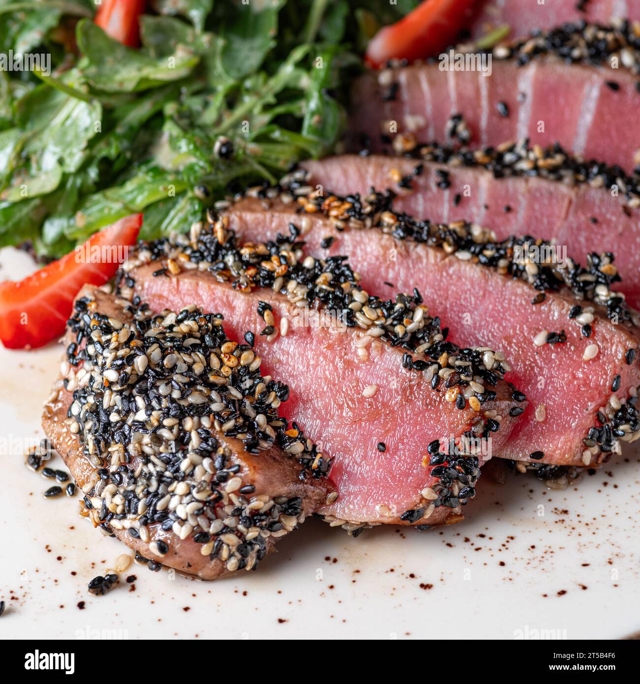 Thunfisch-Tataki in Sesam mit Quinoa und Spinat. Gesundes Essen, Nahaufnahme. Serviert Speisen in einem Restaurant Stockfoto