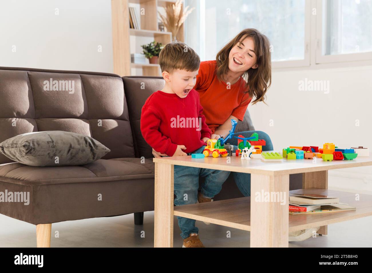 Smiley-Mutter, die den Sohn beim Spielen beobachtet Stockfoto