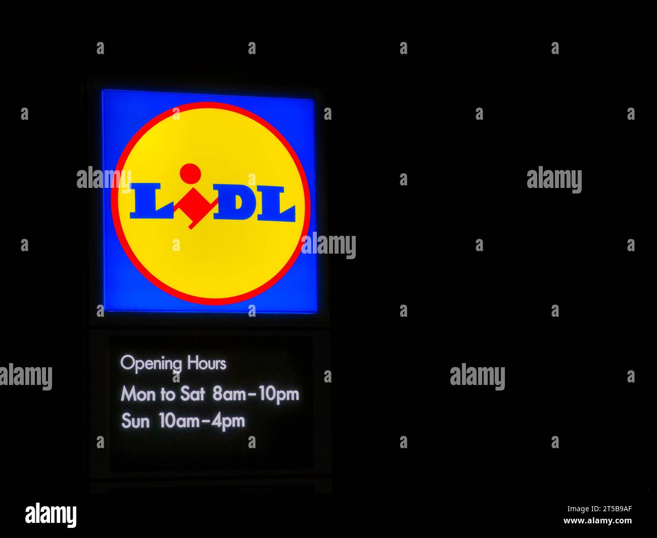 Ein helles Neonschild, das das Firmenlogo des deutschen Discount-Supermarktes Lidl sowie die Öffnungszeiten des Geschäfts zeigt. Nachts aufgenommen. Stockfoto