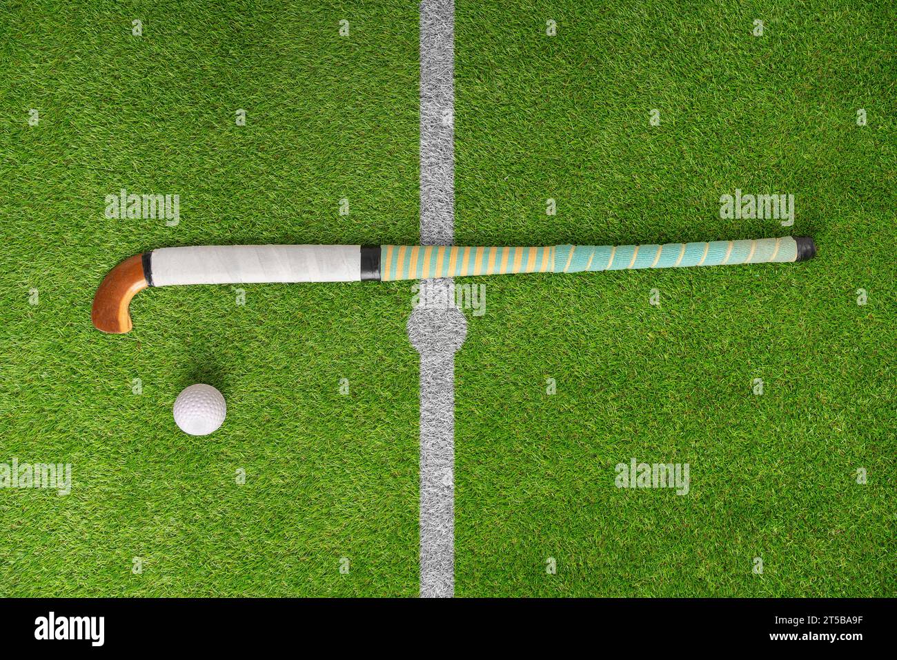 Hockey, Ball und Stick auf grünem Feld, Spielfeld und Ausrüstung vor Grashintergrund. Sportausrüstung, Draufsicht und Astroturf mit in der Praxis, traini Stockfoto