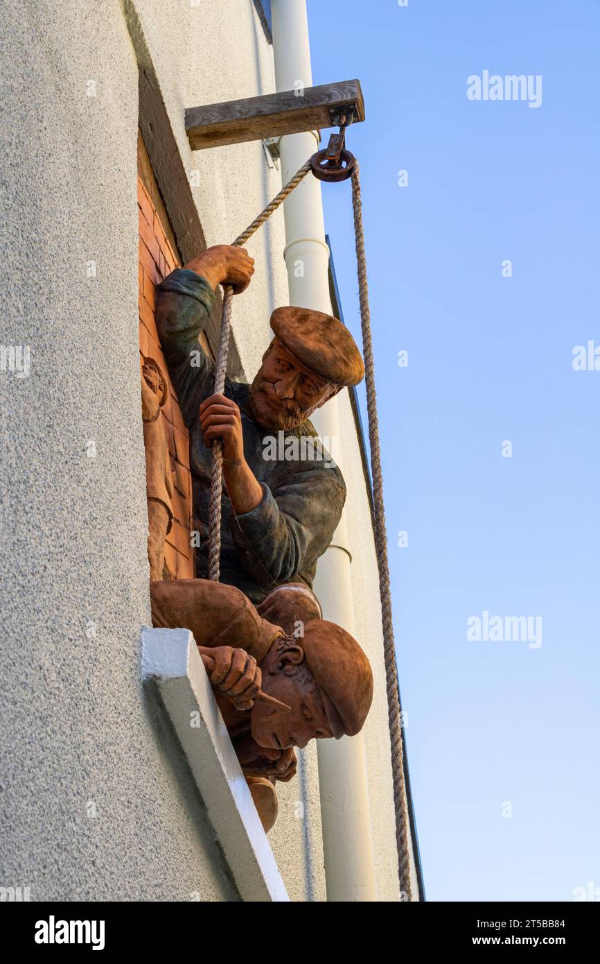 Detaillierte Skulptur der Fischer an der Außenwand eines Cottage in Appledore, Devon Stockfoto
