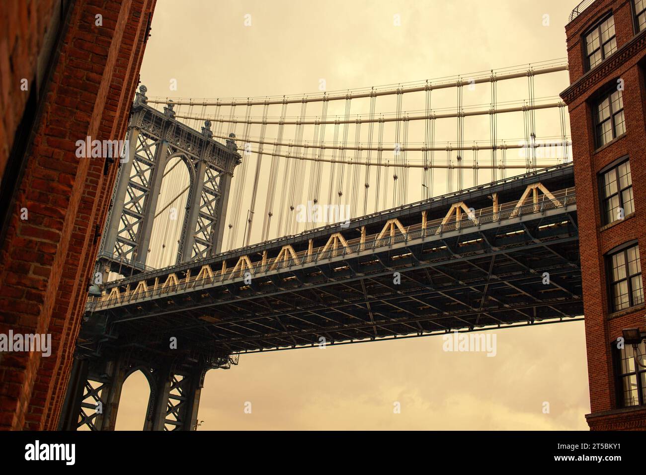 Ein atemberaubendes Stockfoto der berühmten Manhattan Bridge, eingerahmt vom lebhaften Viertel DUMBO in Brooklyn. Das Foto zeigt das Neo-Gothi der Brücke Stockfoto